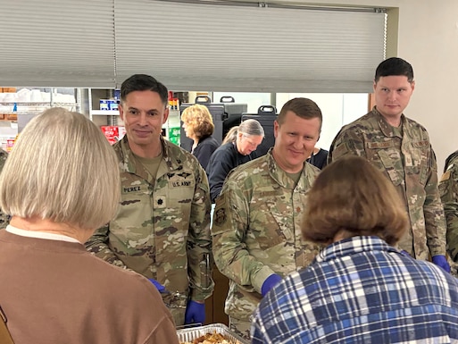 Three men in military uniform stand facing two women, both with neck-length hair.