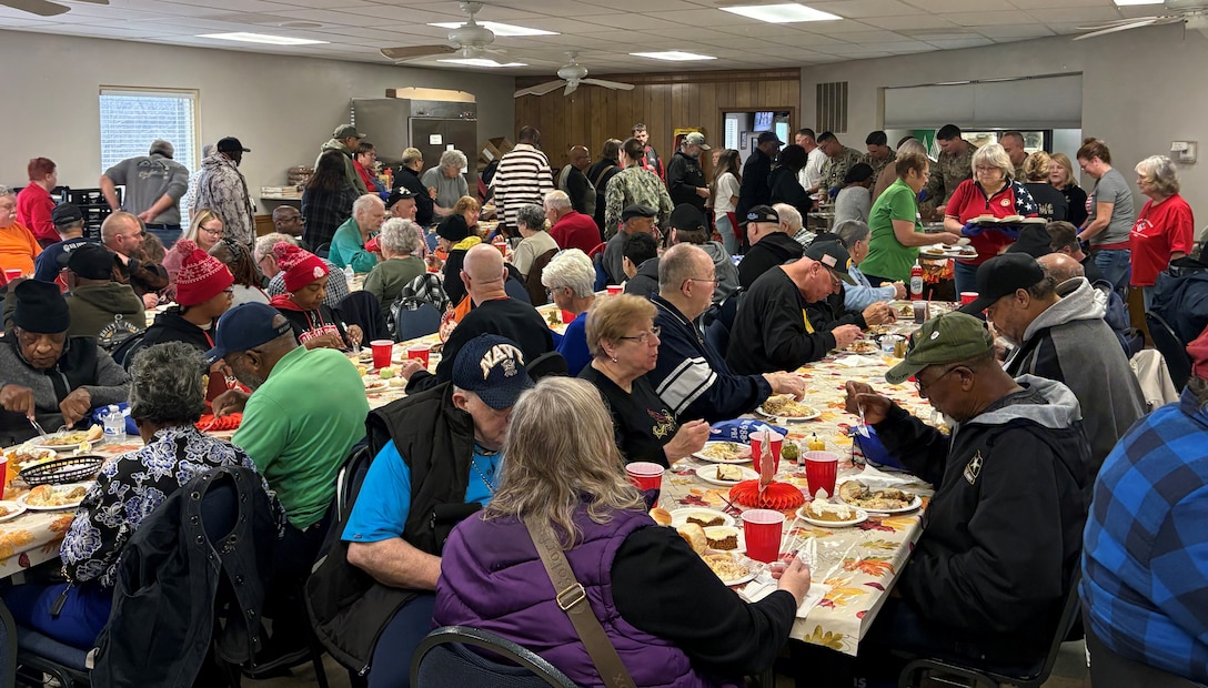 Many people seated at tables with food and red cups - some people standing in back.