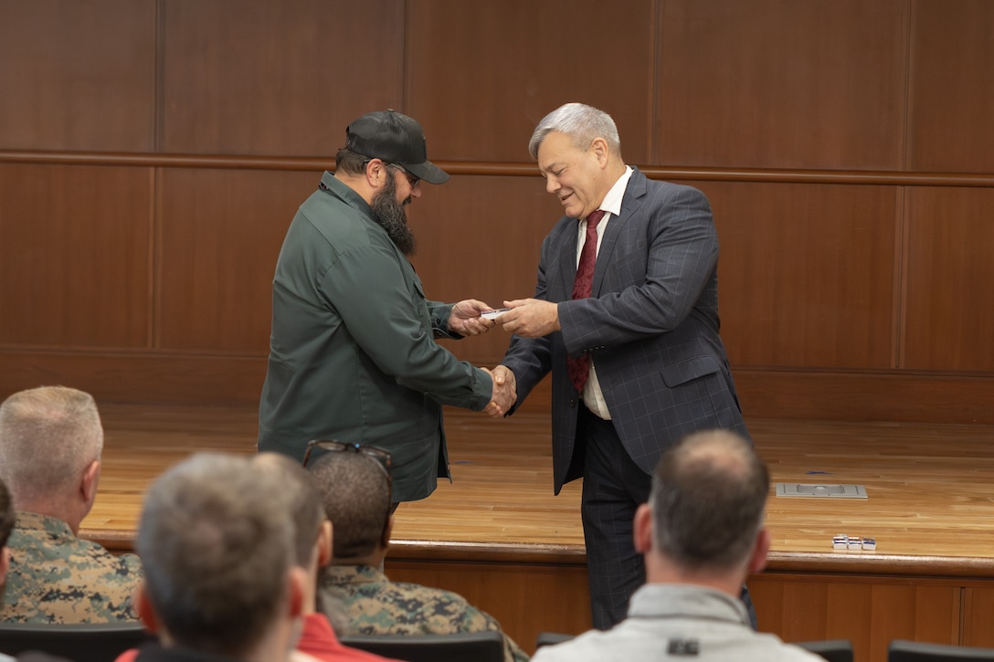 Keven Ezernack, left, is recognized for 25 years of federal service by Gregg Habel, executive director of Marine Forces Reserve and Marine Forces South, during a town hall meeting at the Marine Corps Support Facility New Orleans, Nov. 20, 2025. The town hall meeting addressed improvements to civilian work life at Marine Corps Support Facility New Orleans and future operations within Marine Forces Reserve and Marine Forces South. (U.S. Marine Corps photo by Lance Cpl. Carlina Holland)