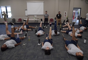People in work out gear lay on the ground and participate in leg lifts.