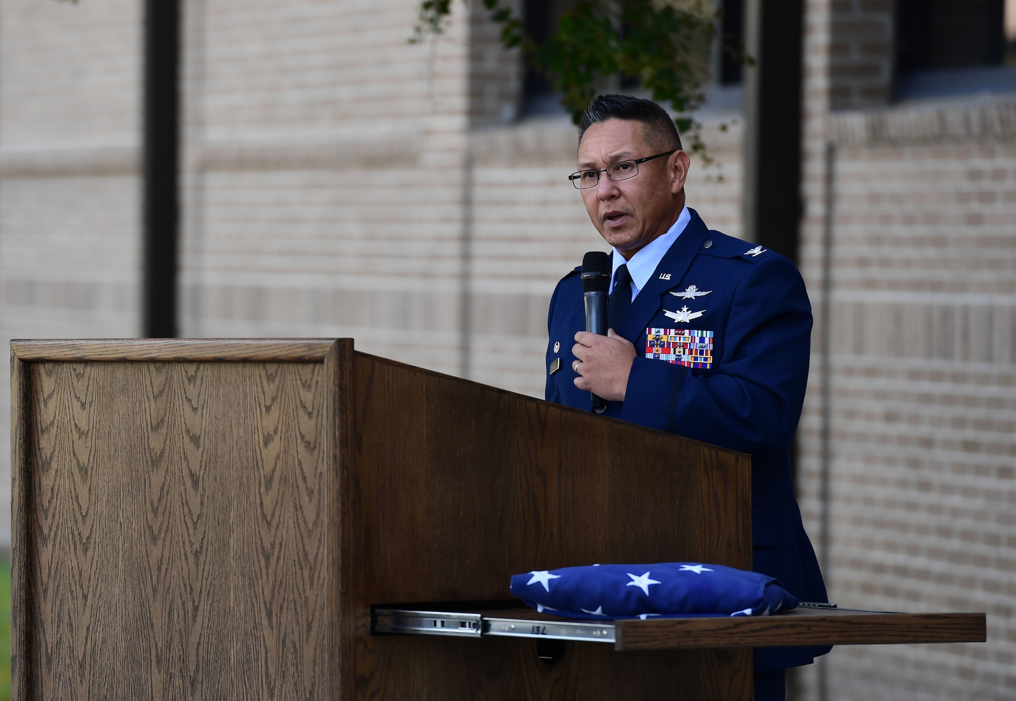 A man wearing a military uniform speaks from behind a podium.