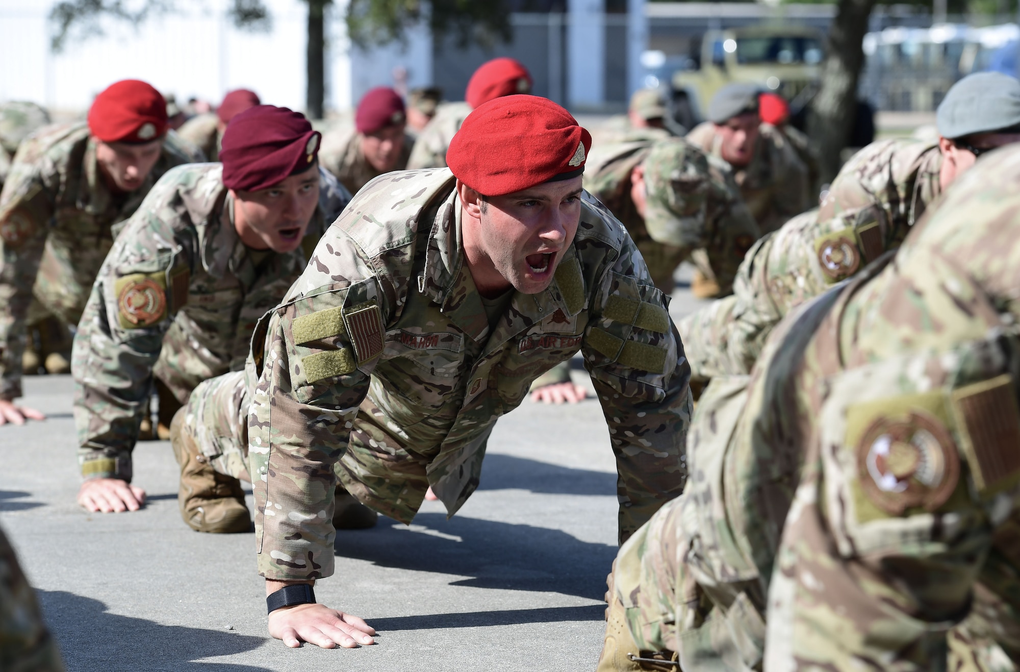 A group of people in military uniforms participate in push-ups