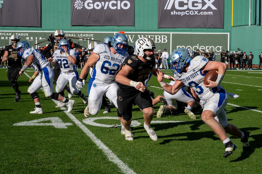 U.S. Coast Guard Academy football players execute a play against the U.S. Merchant Marine Academy during the 54th Secretaries’ Cup at Fenway Park, Boston, Nov. 15, 2025. In 2003, “Secretary’s Cup” was pluralized when the U.S. Coast Guard moved to the Department of Homeland Security. (U.S. Coast Guard photo by Petty Officer Third Class Leo Avila.)