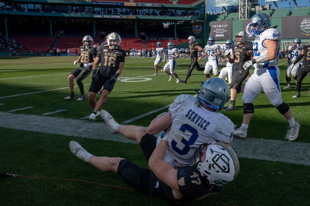 U.S. Coast Guard Academy football player tackles a U.S. Merchant Marine Academy football player during the 54th Secretaries’ Cup at Fenway Park, Boston, Nov. 15, 2025. Fenway Park hosted the 54th Secretaries Cup, giving both service academies a national stage to showcase their hard work and dedication. (U.S. Coast Guard photo by Petty Officer Third Class Leo Avila.)