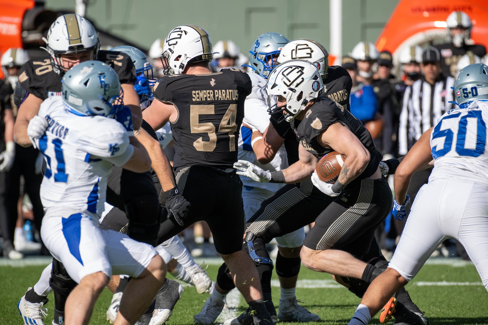U.S. Coast Guard Academy football players execute a play during the 54th Secretaries’ Cup at Fenway Park, Boston, Nov. 15, 2025. In 2003, “Secretary’s Cup” was pluralized when the U.S. Coast Guard moved to the Department of Homeland Security. (U.S. Coast Guard photo by Petty Officer Third Class Leo Avila.)