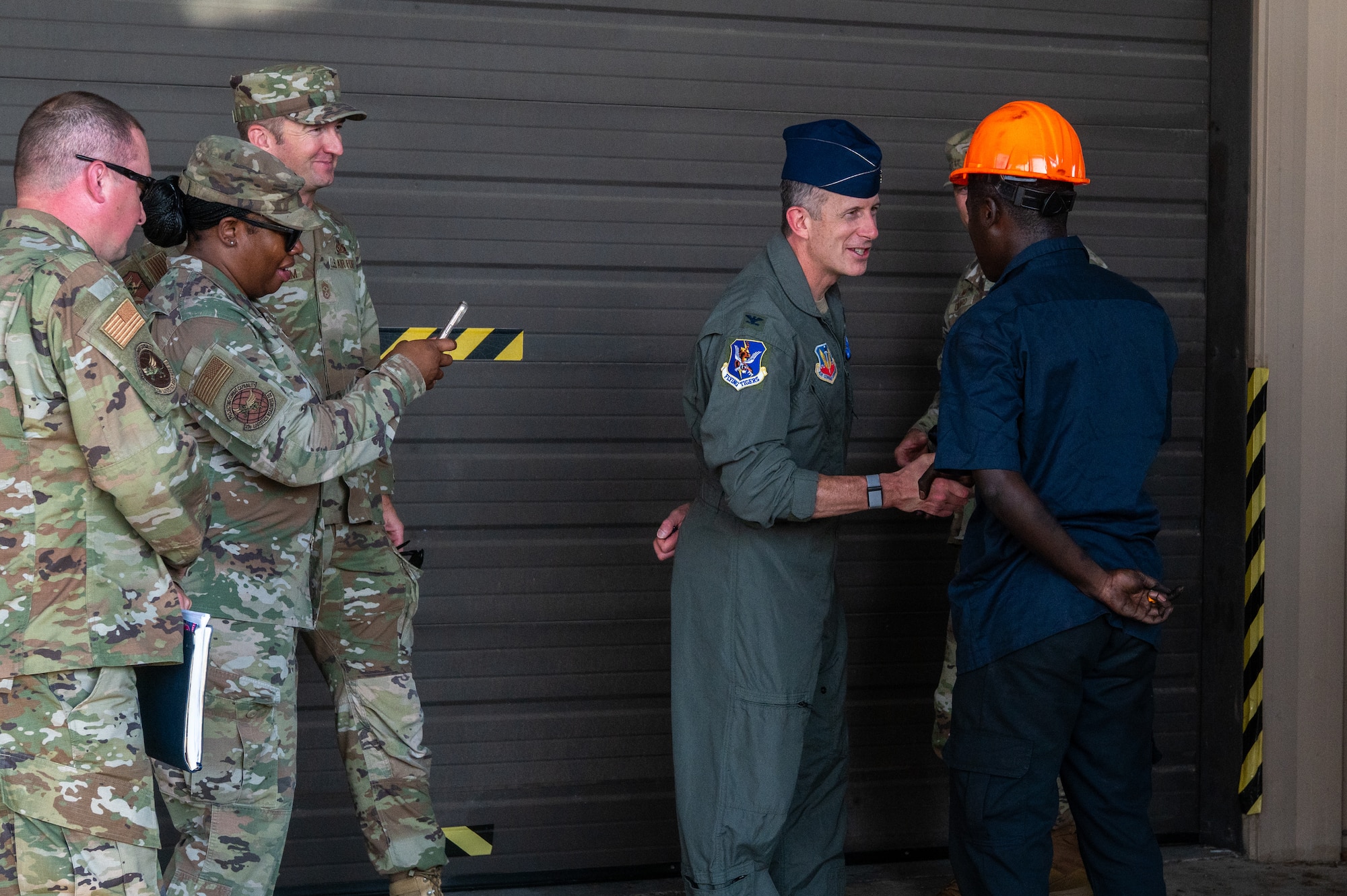 A man shakes hands with another, as a group looks on.