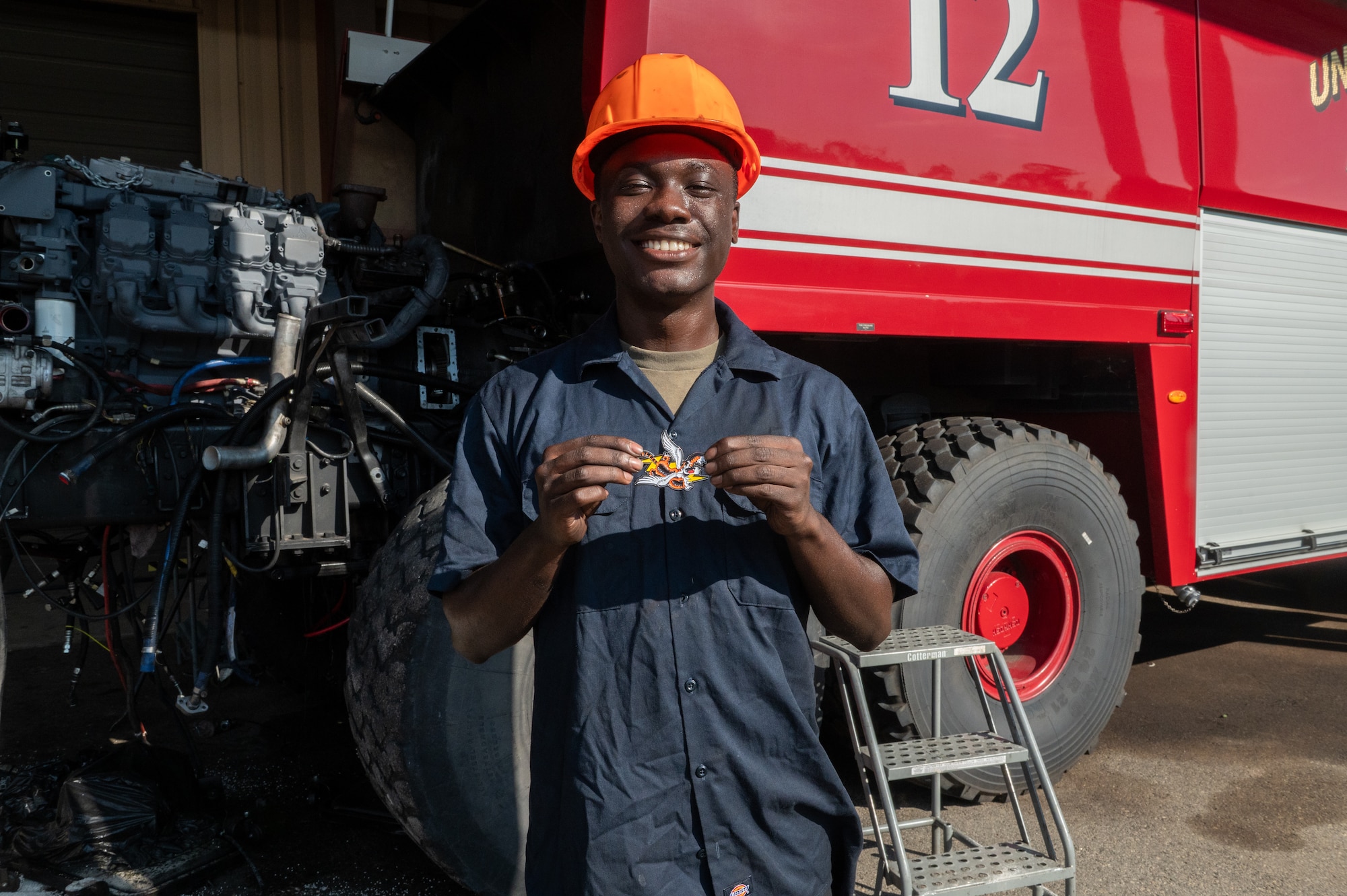 Young man holds up coin while smiling.
