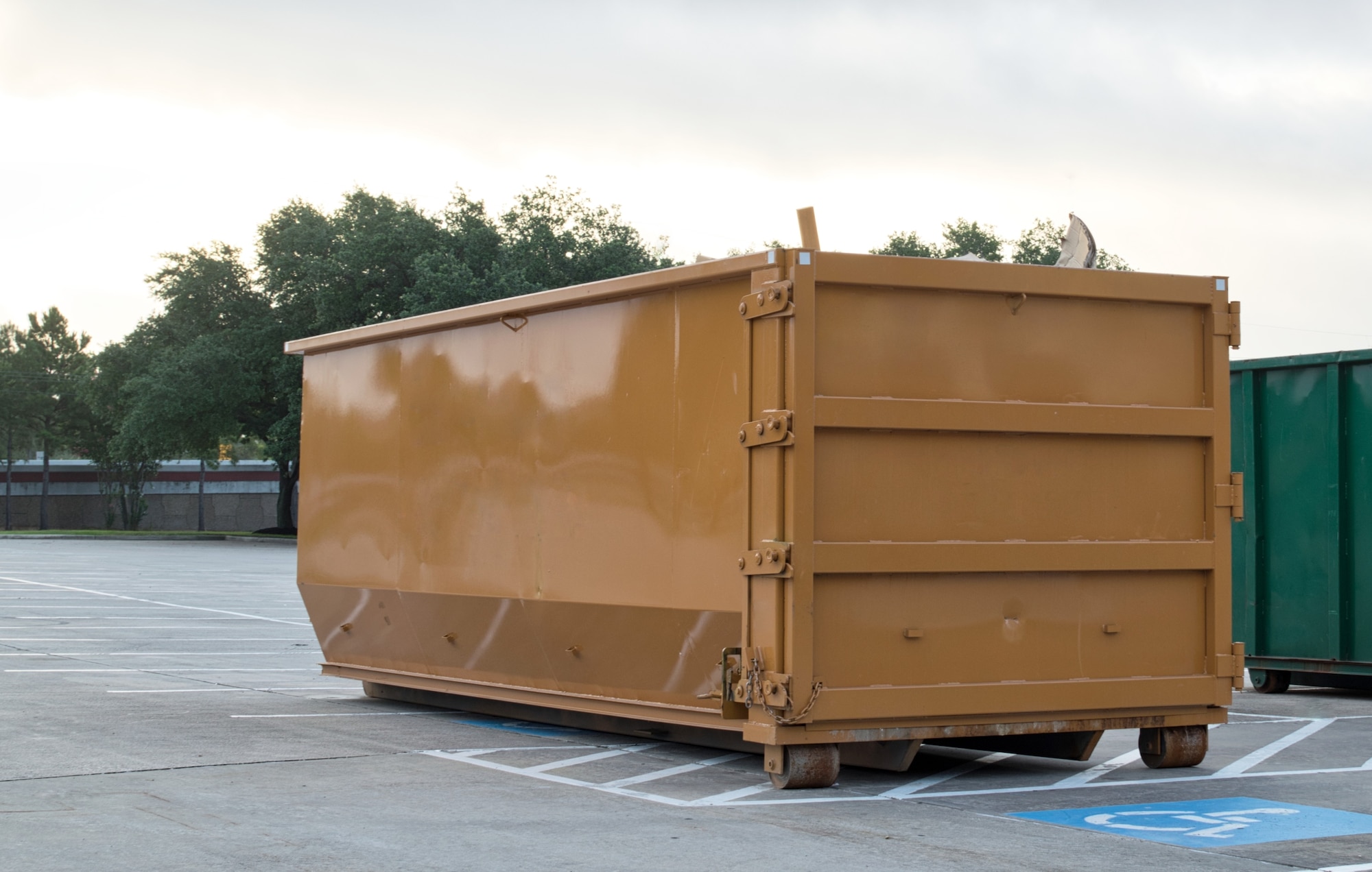 Picture of a brown roll off dumpster in a parking lot