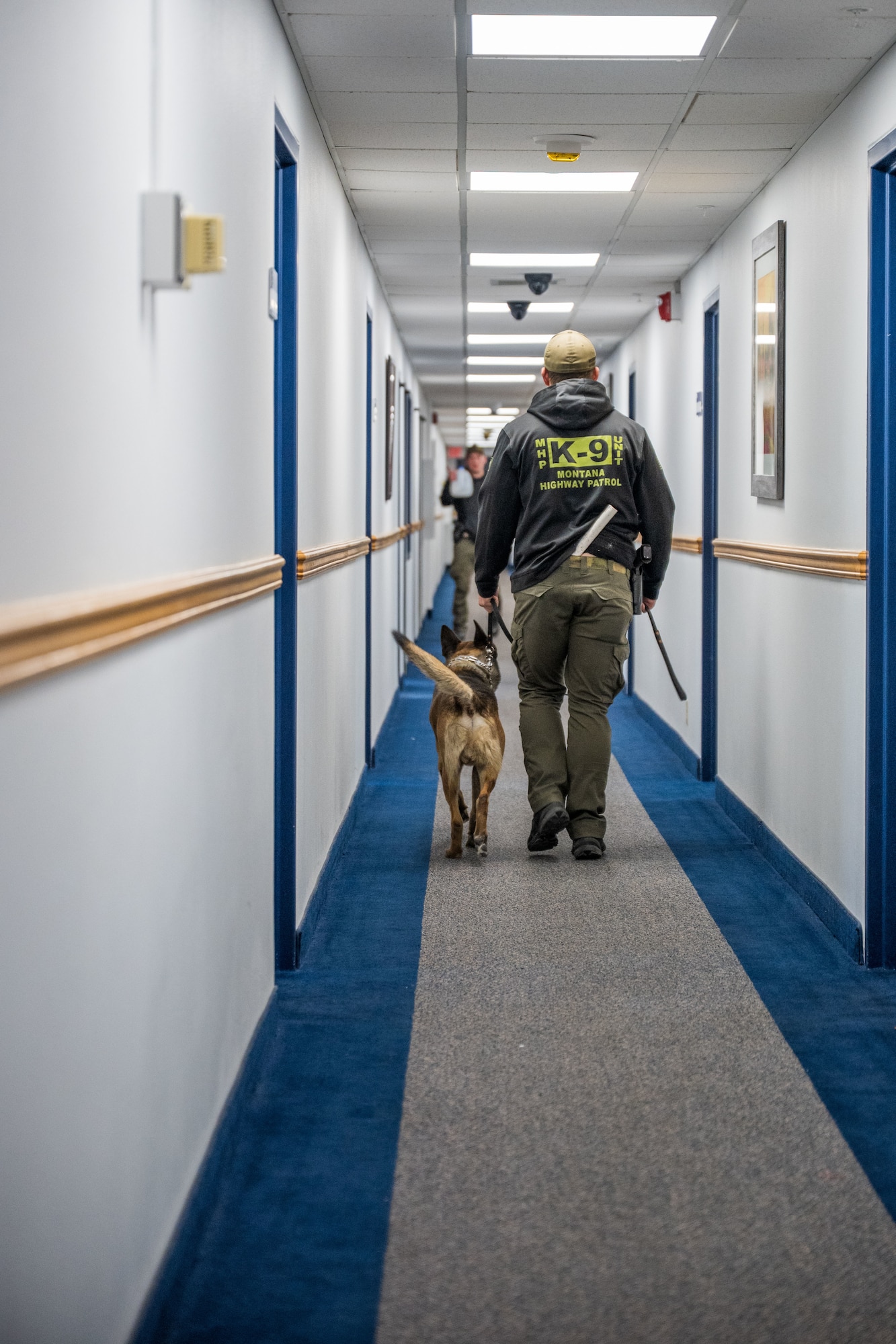 A K-9 Unit walks down a hallway.
