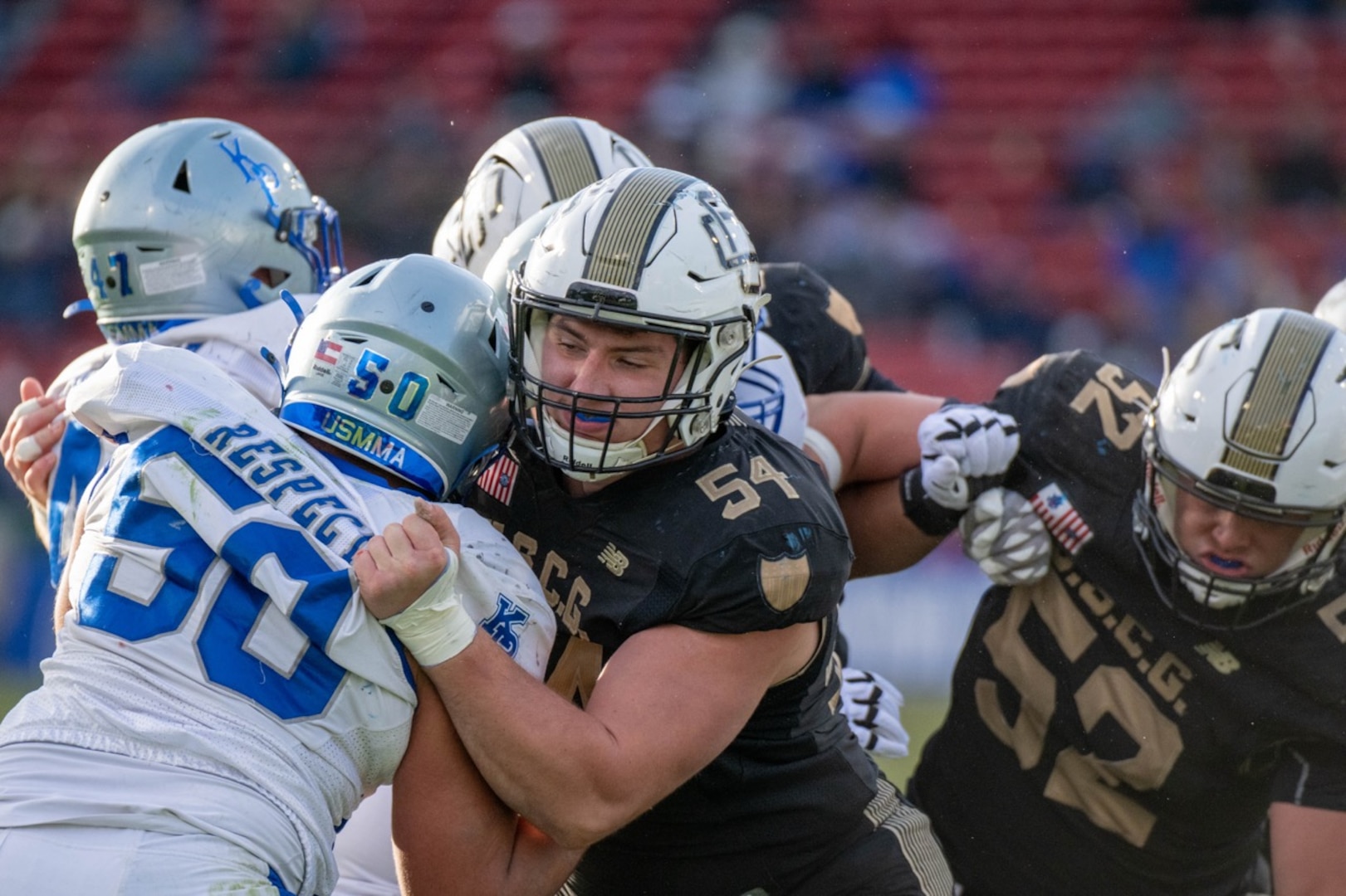 U.S. Coast Guard Academy (USCGA) Cadet First Class Ethan Tabit (#54) holds back a U.S. Merchant Marine Academy (USMMA) football player during the 54th Secretaries' Cup at Fenway Park, Boston, Nov. 15, 2025. The 54th Secretaries' Cup marks the first time USCGA and USMMA have played outside of their home fields for a Secretaries' Cup game. (U.S. Coast Guard photo by Petty Officer Third Class Leo Avila.)