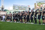 U.S. Coast Guard Academy (USCGA) football team raise their helmets while the USCGA alma mater played, standing on the field during the 54th Secretaries’ Cup at Fenway Park, Boston, Nov. 15, 2025. This is the first time USCGA and the U.S. Merchant Marine Academy have played outside of their home fields for a Secretaries’ Cup game. (U.S. Coast Guard photo by Petty Officer Second Class Janessa Warschkow.)