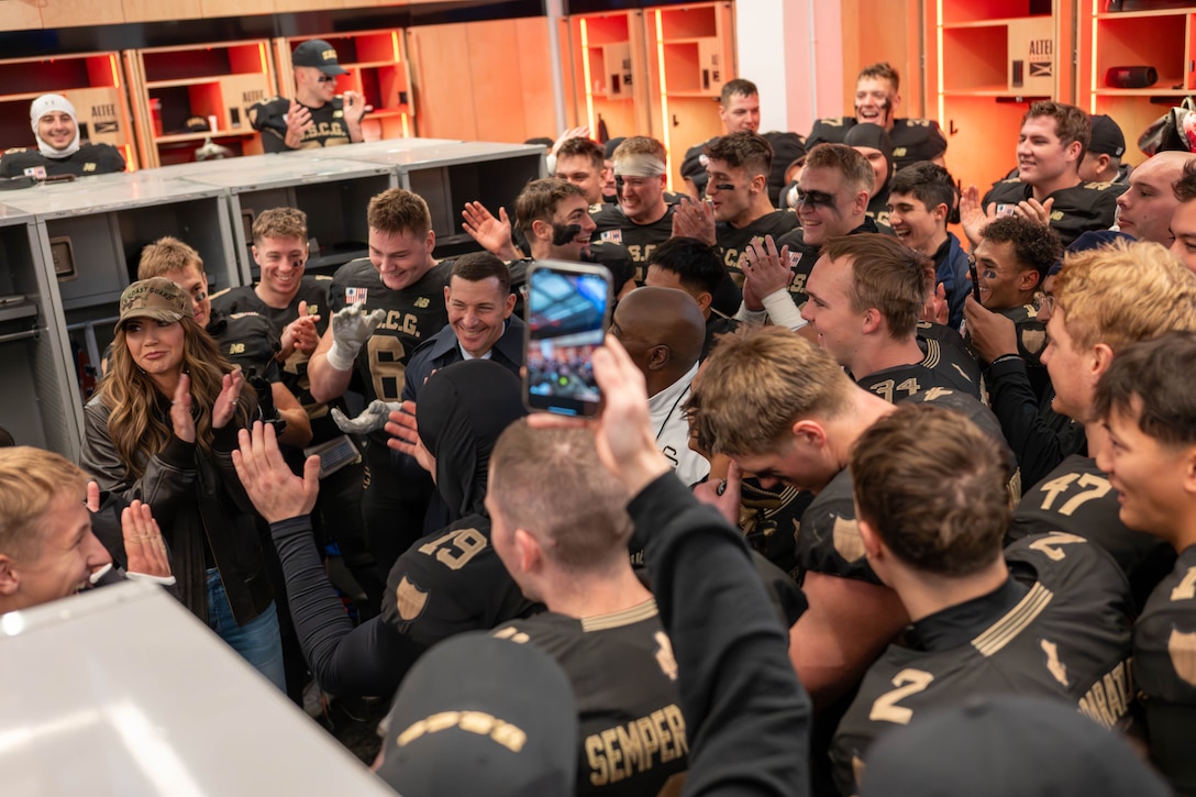 U.S. Department of Homeland Security Secretary Kristi Noem (left) speaks to U.S. Coast Guard Academy football players during the 54th Secretaries’ Cup halftime at Fenway Park, Boston, Nov. 15, 2025. In 2003, “Secretary’s Cup” was pluralized when the U.S. Coast Guard moved to the Department of Homeland Security. (U.S. Coast Guard photo by Petty Officer Second Class Janessa Warschkow.)