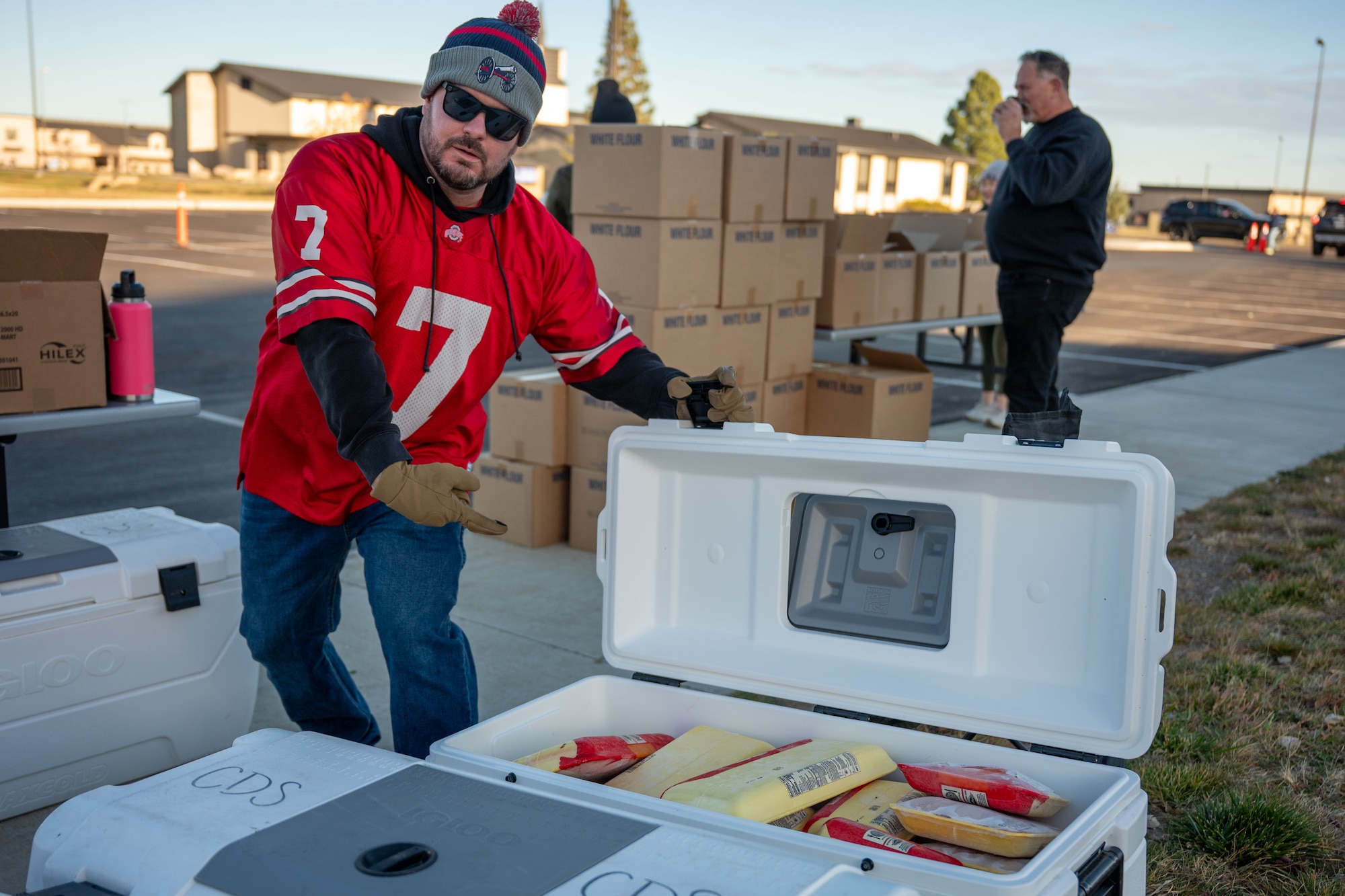 A man pointing at a cooler filled with chicken breasts.