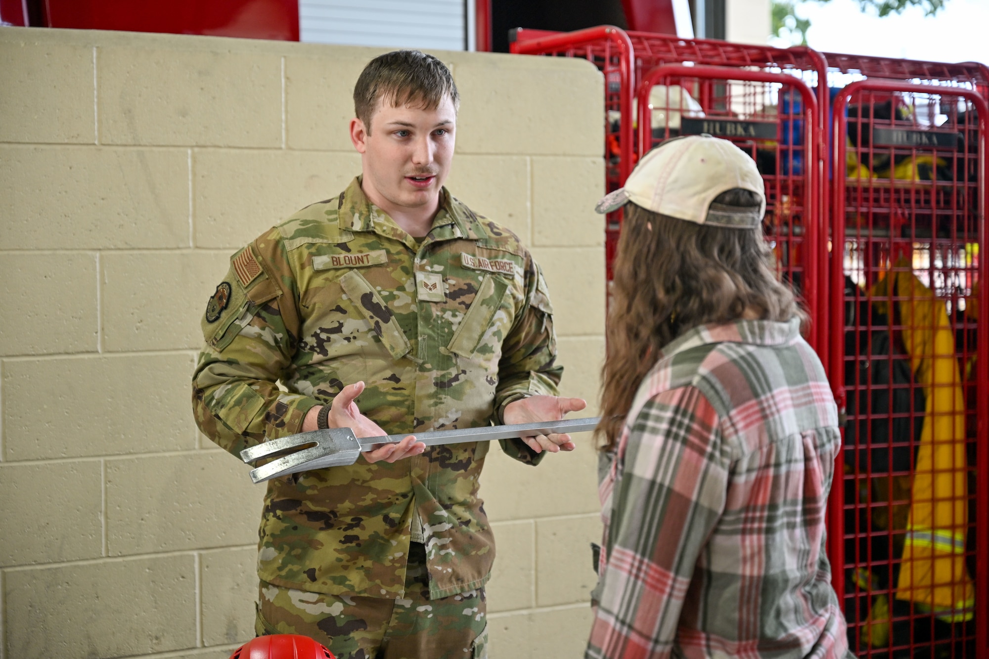 An Airman showing a crowbar to a woman.