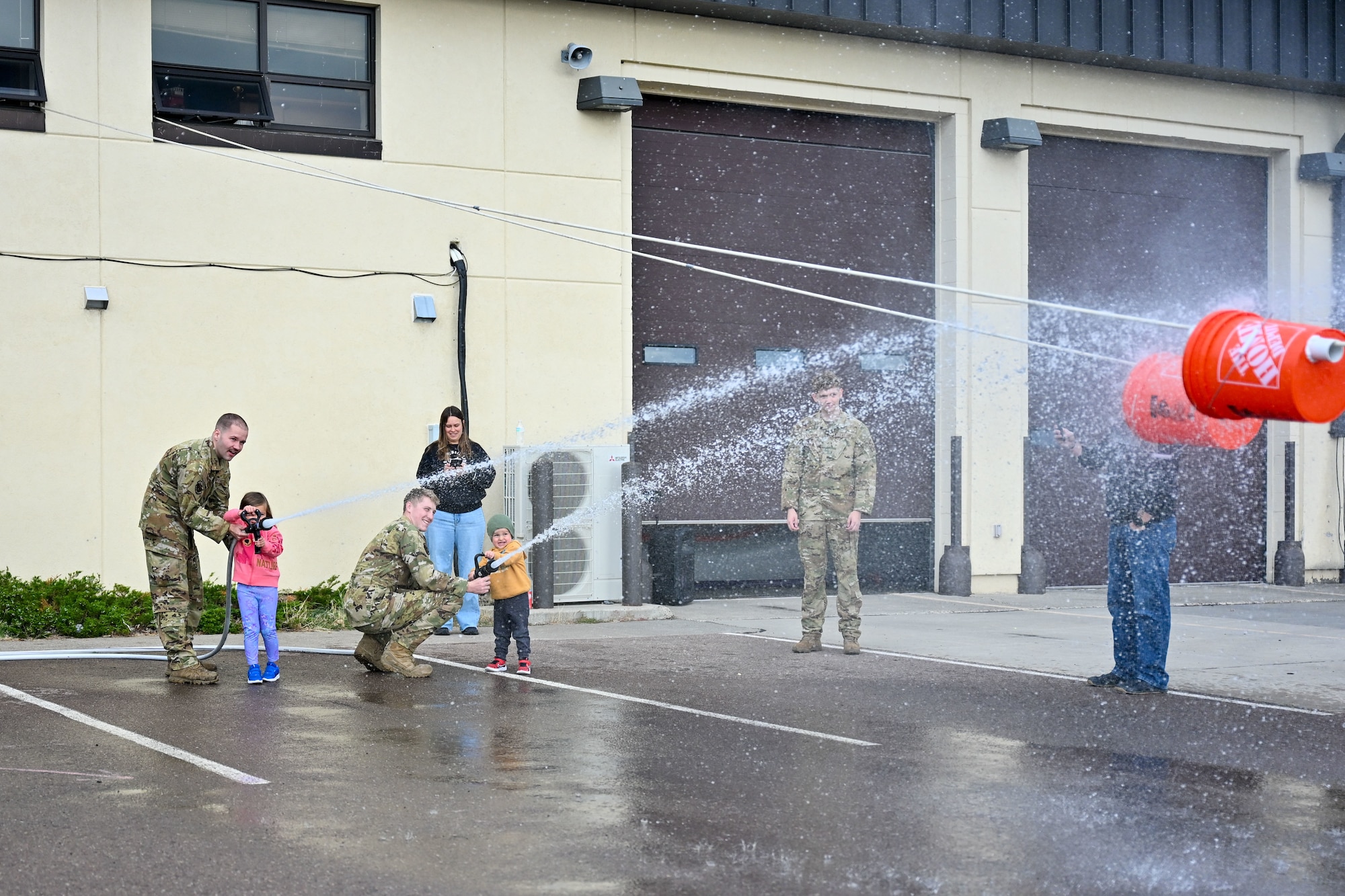 Airmen playing with water hoses with kids.