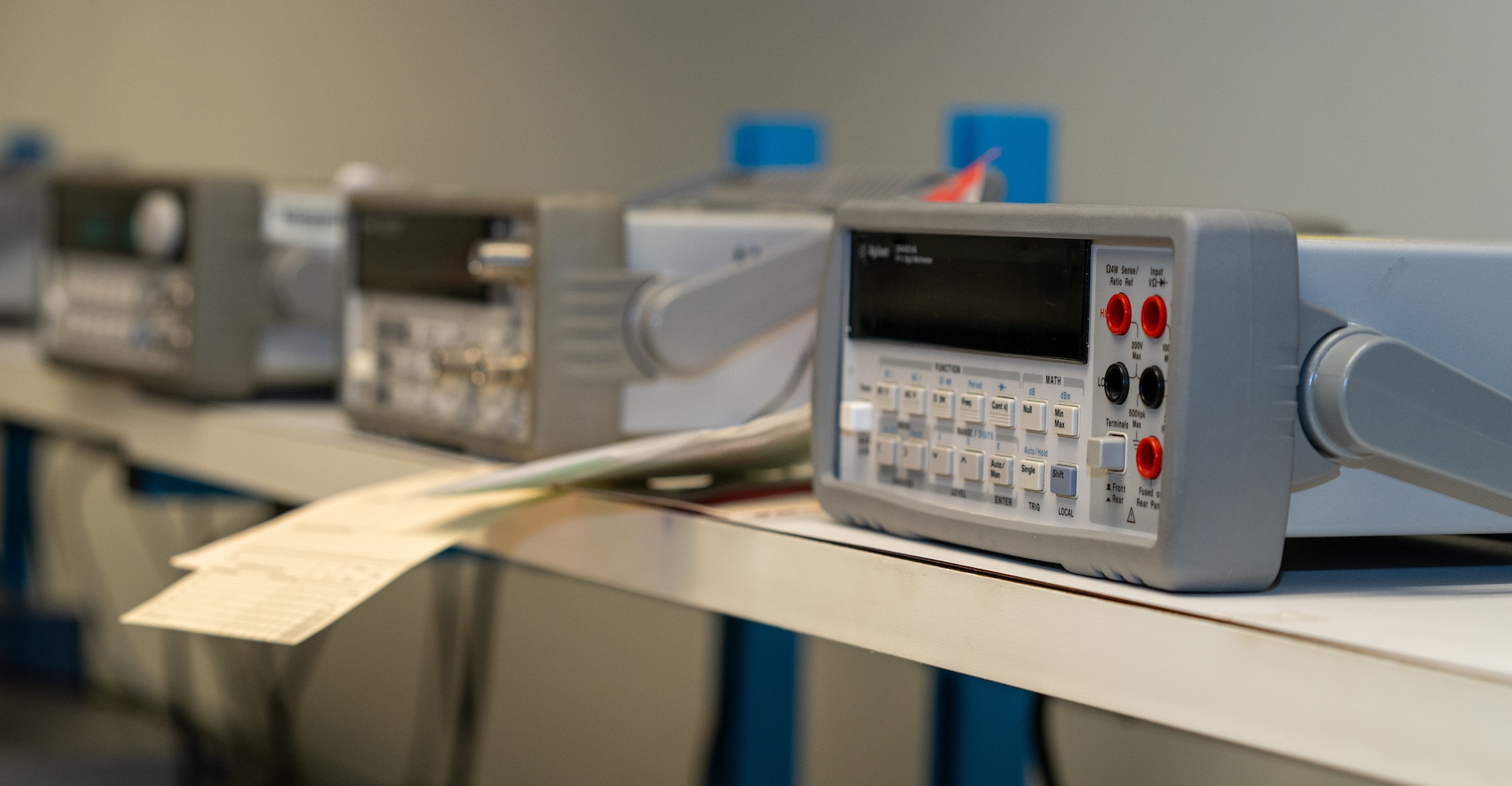 A row of multimeters on a shelf.