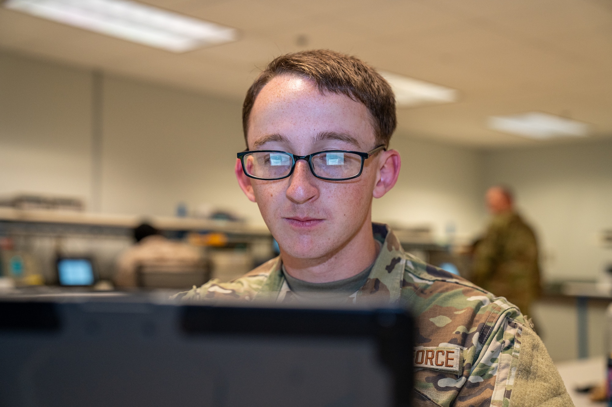 A serviceman in OCPs looks at a computer screen.