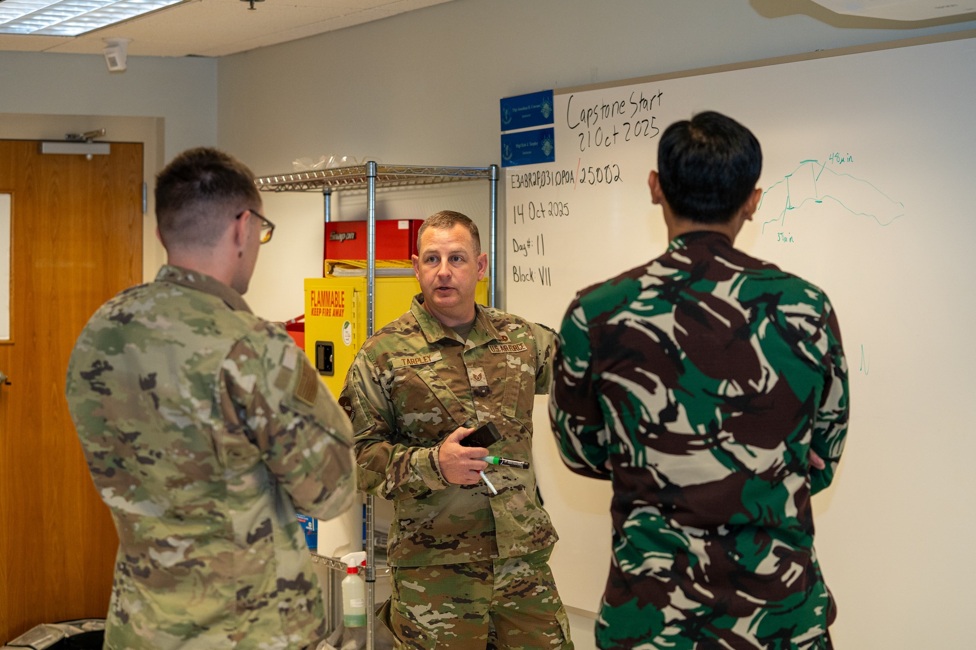 Service members in OCPs sit in a classroom.