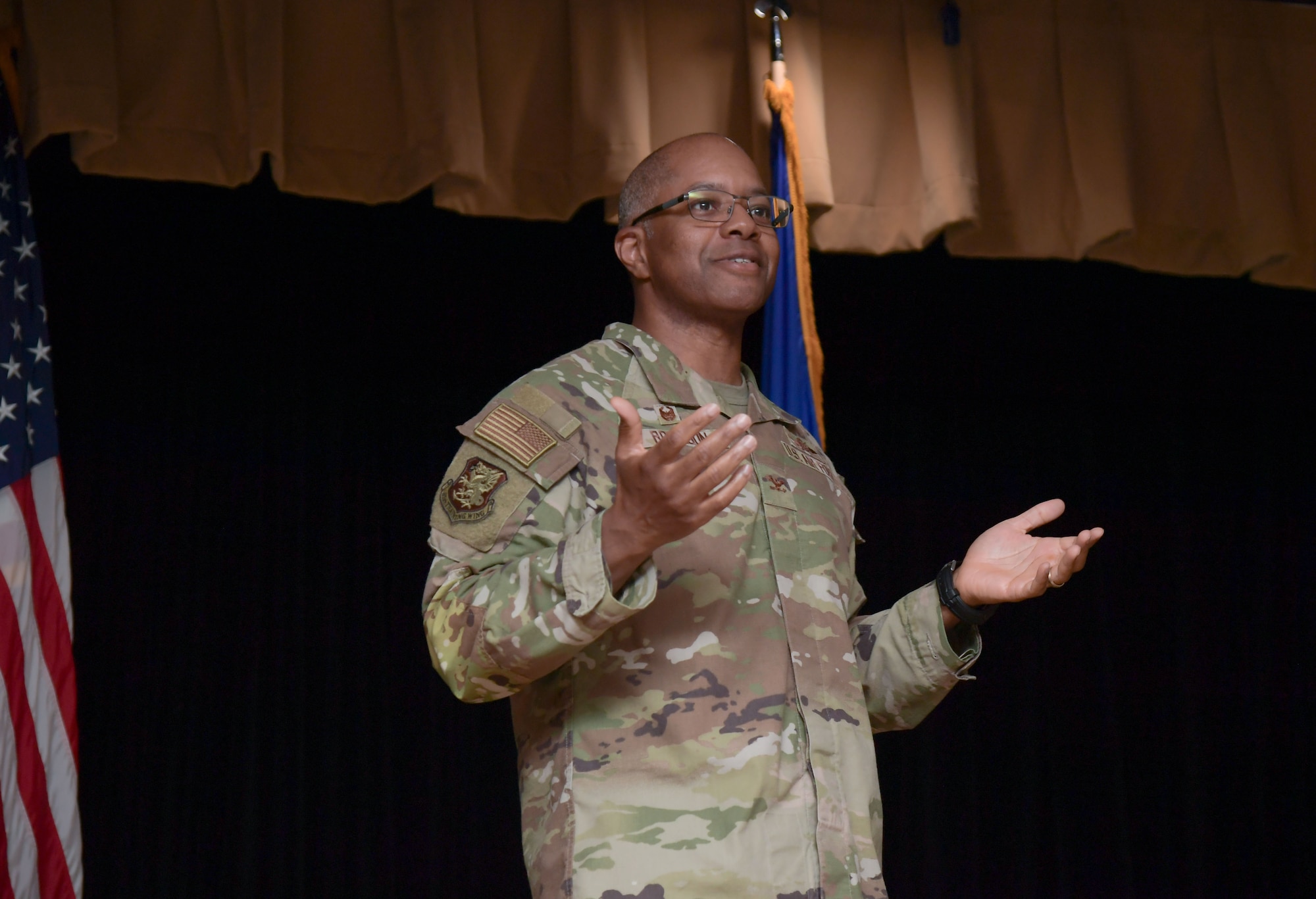A man wearing a military uniform speaks from a stage