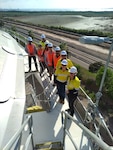 RDML Bresnihan (left) ascends a large storage tank at the site of a future fueling facility near Port Darwin.