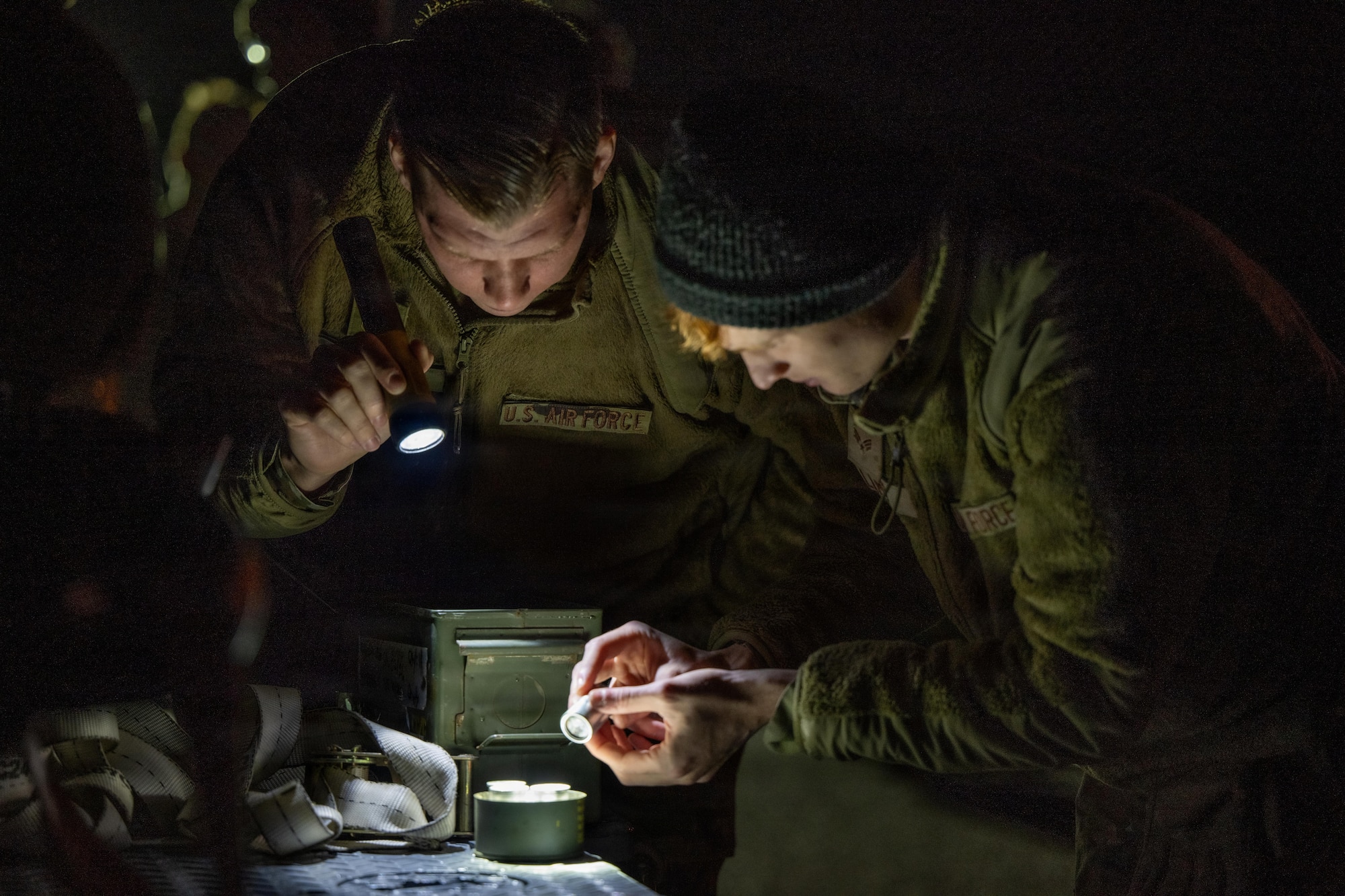 Airmen prepare to load a large weapon onto a B-1 Lancer outside on the flightline