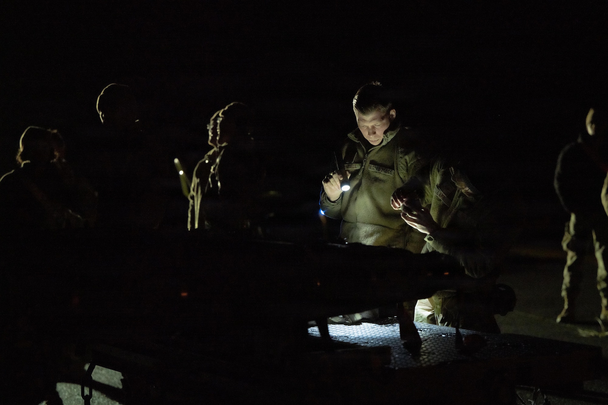 Airmen prepare to load a large weapon onto a B-1 Lancer outside on the flightline