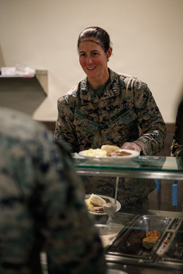 U.S. Marine Corps Capt. Kelly Owen, an infantry officer and the executive officer of Company D, Basic Officer Course 4-25, The Basic School, serves food during the Warrior’s Breakfast at TBS, Marine Corps Base Quantico, Virginia, Nov. 20, 2025. The Warrior’s breakfast follows the Warfighting Field Exercise, which serves as the culminating event at TBS, evaluating students’ proficiency in decision-making, small-unit tactics, and leadership as they operate under sustained physical and mental pressure in a realistic warfighting scenario. (U.S. Marine Corps photo by Cpl. Joshua Barker)