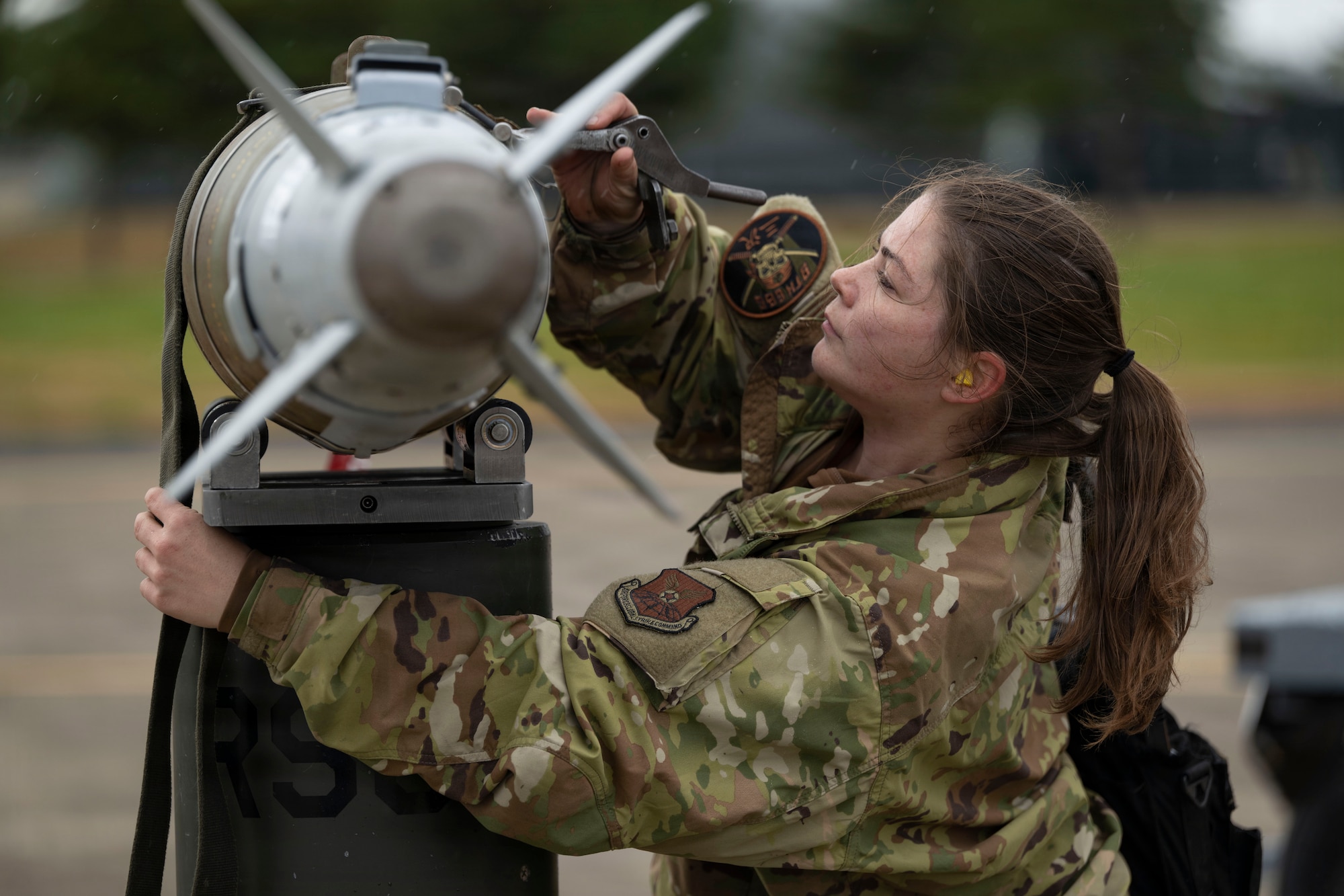 Airmen prepare to load a large weapon onto a B-1 Lancer outside on the flightline