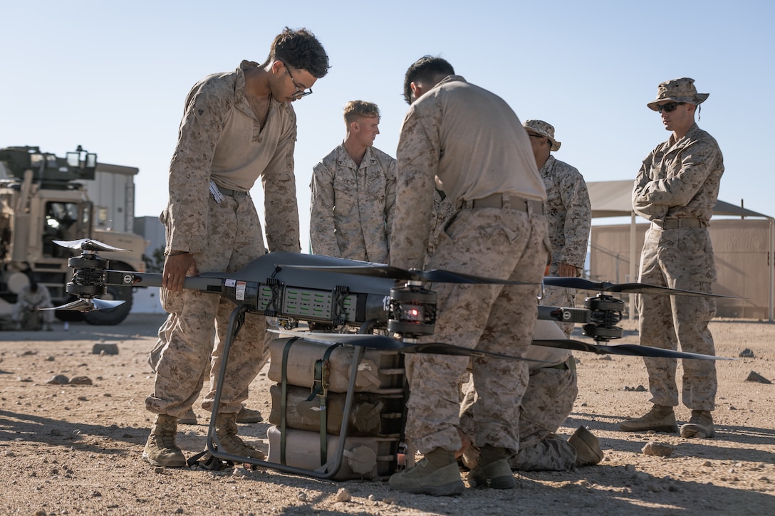 U.S. Marines with Combat Logistics Battalion 7, Combat Logistics Regiment 1, 1st Marine Logistics Group, load water jugs onto the Tactical Resupply Unmanned Air System at Range 800, Marine Corps Air Ground Combat Center, Twentynine Palms, California, Sept. 24, 2025. The goal of the TRUAS is to be integrated within logistics formations as a tool for company and platoon commanders to conduct rapid resupply to small units in hard-to-reach locations. (U.S. Marine Corps photo by Cpl. Damian Oso)