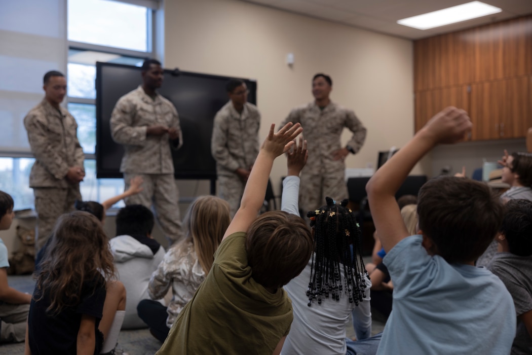 Students raise their hands for U.S. Marines with 3rd Light Armored Reconnaissance Battalion, 1st Marine Division, I Marine Expeditionary Force, during an Adopt a School Physical Education Program Joshua Tree Elementary School, Joshua Tree, California, Sept. 26, 2025. The Marines volunteer with the JTES PE program to provide leadership and positive role modeling to inspire students. (U.S. Marine Corps photo by Lance Cpl. Saige Steiber)