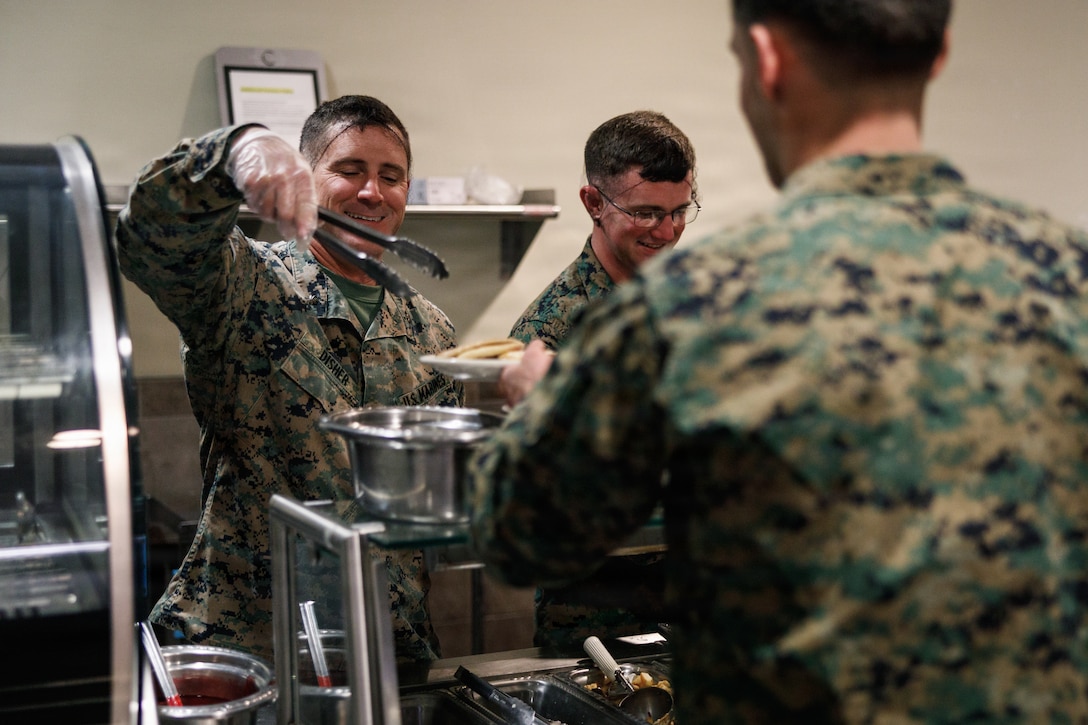 U.S. Marine Corps Maj. Brett Disher, company commander, Company D, Basic Officer Course 4-25, The Basic School, serves food during the Warrior’s Breakfast at TBS, Marine Corps Base Quantico, Virginia, Nov. 20, 2025. The Warrior’s breakfast follows the Warfighting Field Exercise, which serves as the culminating event at TBS, evaluating students’ proficiency in decision-making, small-unit tactics, and leadership as they operate under sustained physical and mental pressure in a realistic warfighting scenario. (U.S. Marine Corps photo by Cpl. Joshua Barker)