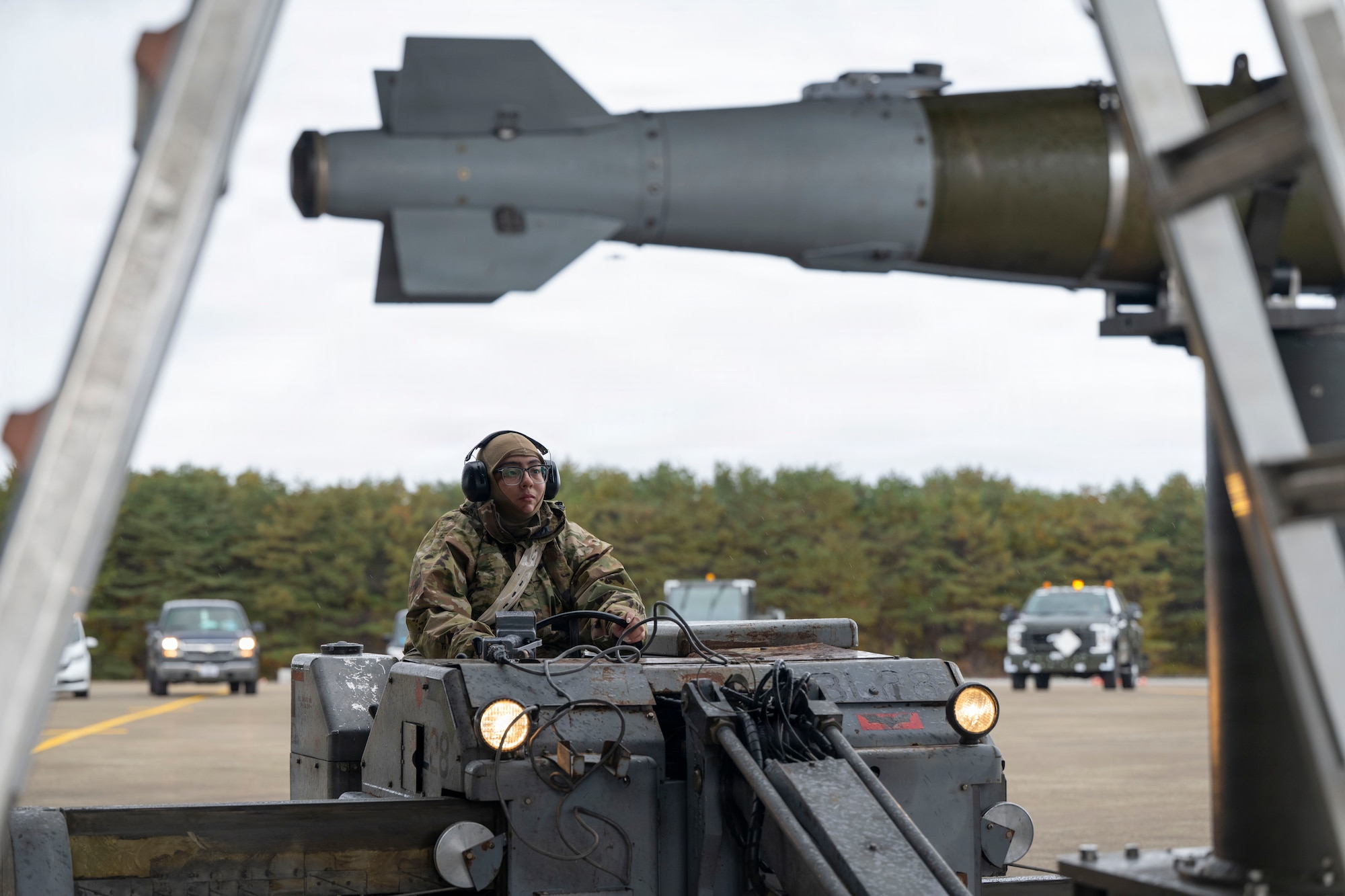 Airmen prepare to load a large weapon onto a B-1 Lancer outside on the flightline