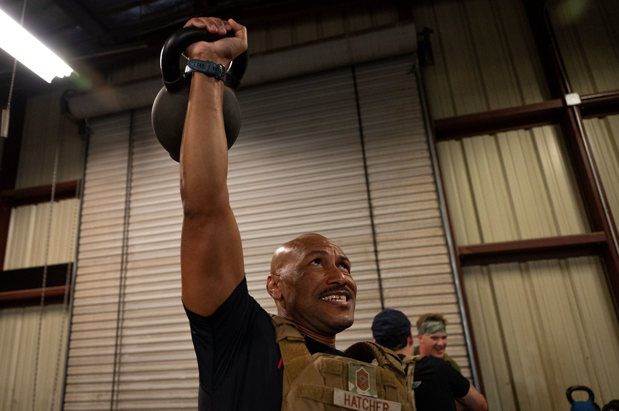 U.S. Air Force Chief Master Sgt. Kelvin Hatcher, 355th Wing command chief, performs a single-arm kettlebell press during theSalute in Motion memorial at Davis-Monthan Air Force Base, Arizona, Nov. 21, 2025. Hatcher’s participation demonstrated his commitment to unit readiness and lethality. (U.S. Air Force photo by Airman 1st Class Jaden Kidd)