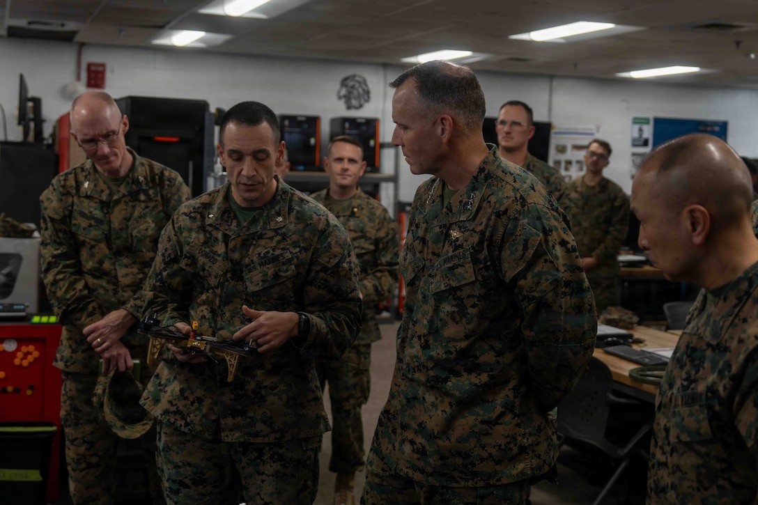 U.S. Marine Corps Lt. Col. Joussef J. Abchi Donado, commanding officer for 2nd Maintenance Battalion, 2nd Marine Logistics Group, center left, briefs the capabilities of a small unmanned aerial system to Lt. Gen. Eric Austin, Combat Development and Integration deputy commandant, during a tour of the II Marine Expeditionary Force Innovation Campus at Marine Corps Base Camp Lejeune, North Carolina, Nov. 20, 2025. Austin met with leaders of 2nd MLG to speak about force design and 2nd MLG’s capabilities and efforts to innovate as well as touring the II MEF innovation campus. (U.S. Marine Corps photo by Sgt. Rafael Brambila-Pelayo)