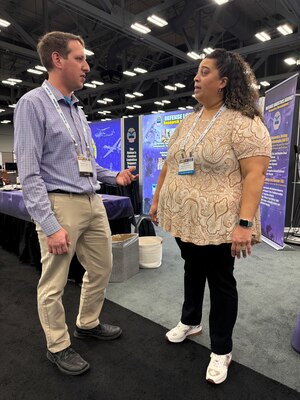 Mattthew Borsinger, left, and Danielle Williams, right, discuss the Defense Logistics Agency Enterprise Rotation Program at the Defense Manufacturing Conference in Austin, Texas, Dec. 2, 2024. (DLA photo by Nutan Chada)