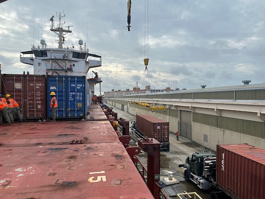 A shipping vessel being loaded while at port.