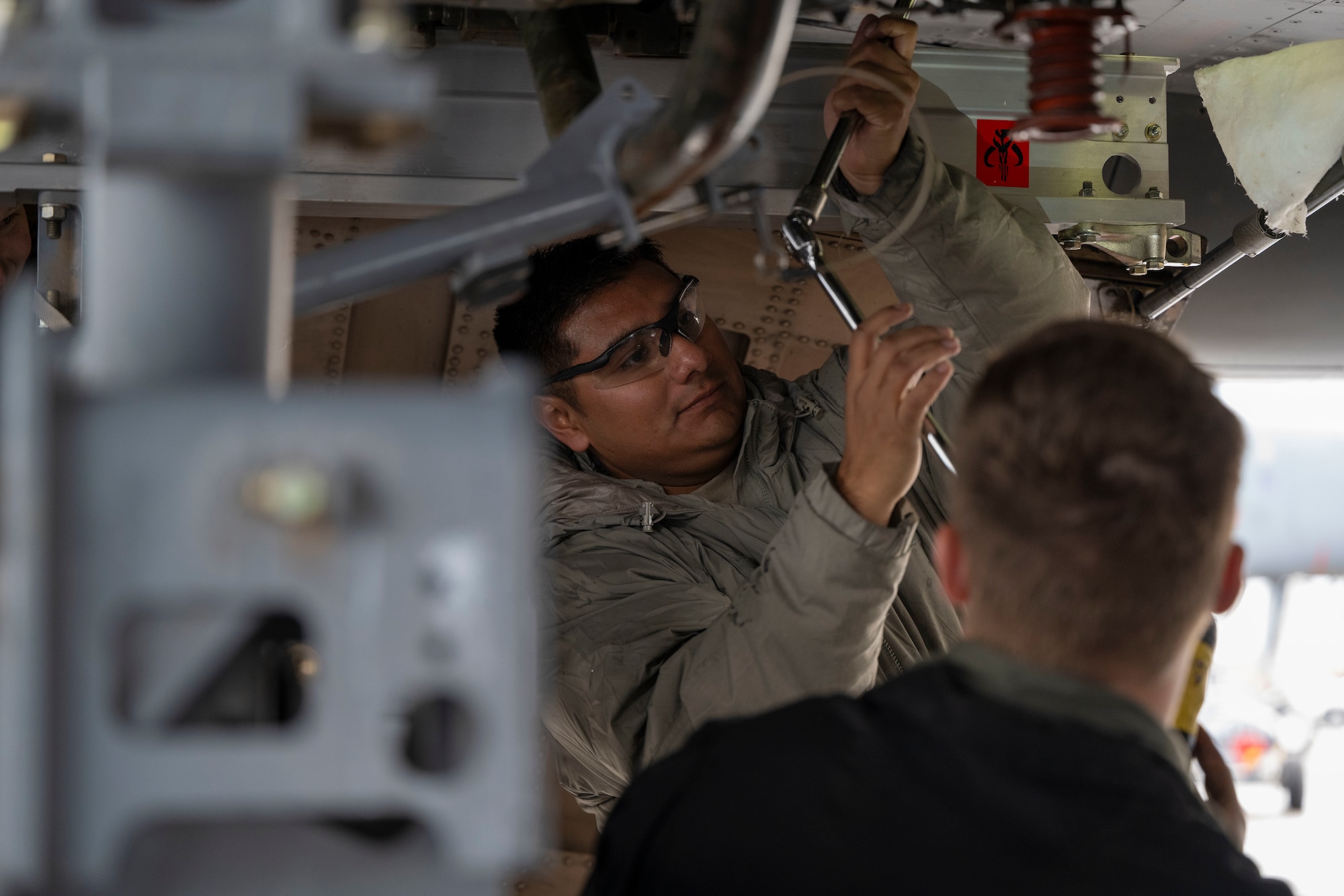 Airmen conduct maintenance on a B-1 Lancer outside in the daylight after raining outside