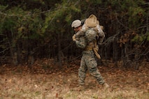 A U.S. Marine Corps student with Company D, Basic Officer Course 4-25, The Basic School,  conducts a fireman carry during the Warfighting Field Exercise at Marine Corps Base Quantico, Virginia, Nov. 18, 2025. The WARFEX serves as the culminating event at TBS, evaluating students’ proficiency in decision-making, small-unit tactics, and leadership as they operate under sustained physical and mental pressure in a realistic warfighting scenario. (U.S. Marine Corps photo by Cpl. Joshua Barker)