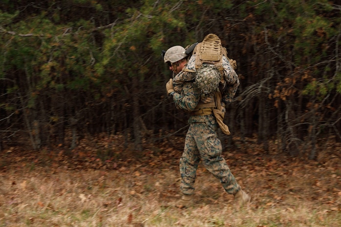 A U.S. Marine Corps student with Company D, Basic Officer Course 4-25, The Basic School,  conducts a fireman carry during the Warfighting Field Exercise at Marine Corps Base Quantico, Virginia, Nov. 18, 2025. The WARFEX serves as the culminating event at TBS, evaluating students’ proficiency in decision-making, small-unit tactics, and leadership as they operate under sustained physical and mental pressure in a realistic warfighting scenario. (U.S. Marine Corps photo by Cpl. Joshua Barker)