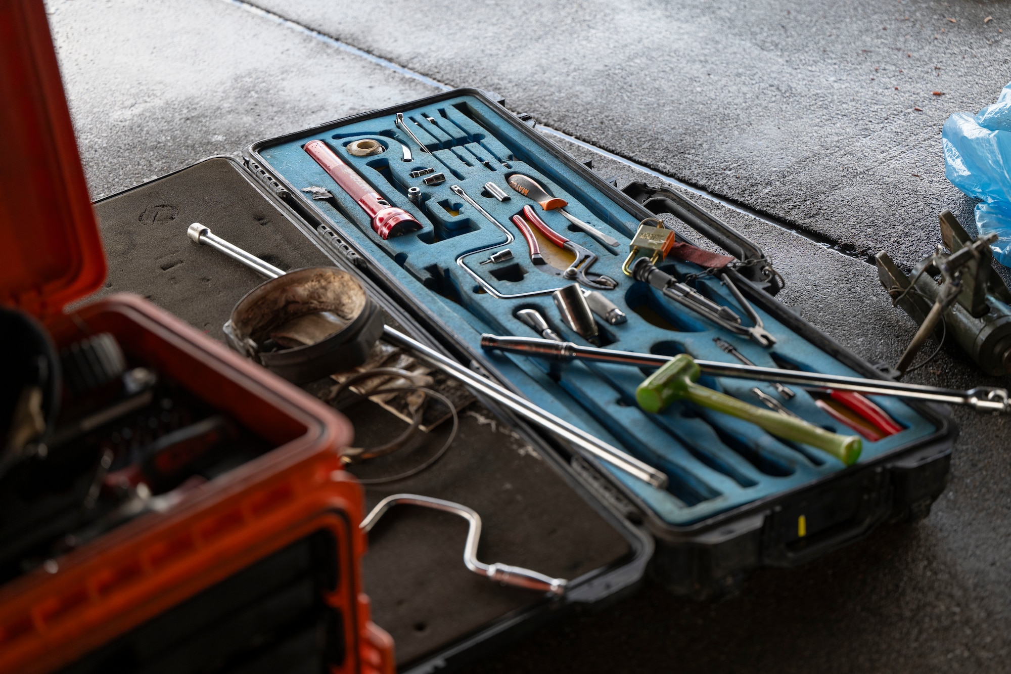 Airmen conduct maintenance on a B-1 Lancer outside in the daylight after raining outside