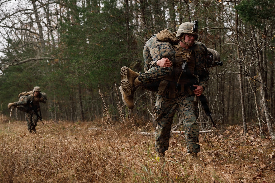 U.S. Marine Corps students with Company D, Basic Officer Course 4-25, The Basic School,  conduct a fireman carry during the Warfighting Field Exercise at Marine Corps Base Quantico, Virginia, Nov. 18, 2025. The WARFEX serves as the culminating event at TBS, evaluating students’ proficiency in decision-making, small-unit tactics, and leadership as they operate under sustained physical and mental pressure in a realistic warfighting scenario. (U.S. Marine Corps photo by Cpl. Joshua Barker)