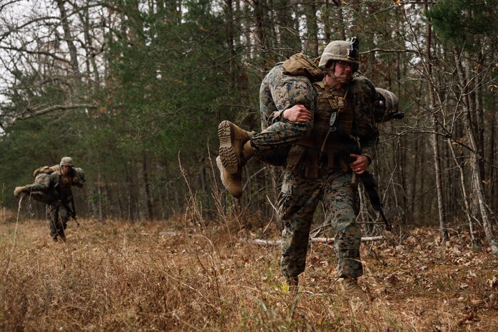 U.S. Marine Corps students with Company D, Basic Officer Course 4-25, The Basic School,  conduct a fireman carry during the Warfighting Field Exercise at Marine Corps Base Quantico, Virginia, Nov. 18, 2025. The WARFEX serves as the culminating event at TBS, evaluating students’ proficiency in decision-making, small-unit tactics, and leadership as they operate under sustained physical and mental pressure in a realistic warfighting scenario. (U.S. Marine Corps photo by Cpl. Joshua Barker)