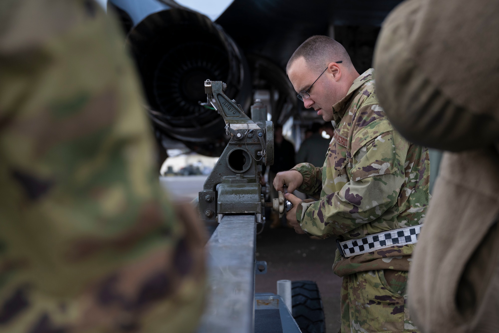 Airmen conduct maintenance on a B-1 Lancer outside in the daylight after raining outside