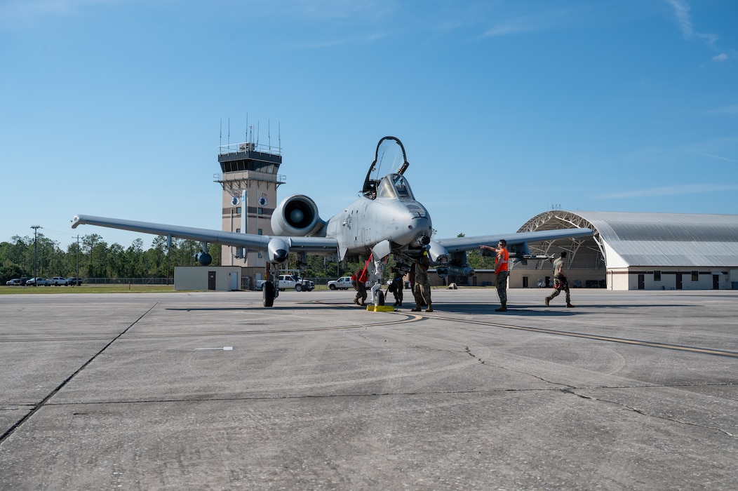 Aircraft sits on tarmac as people walk around it.