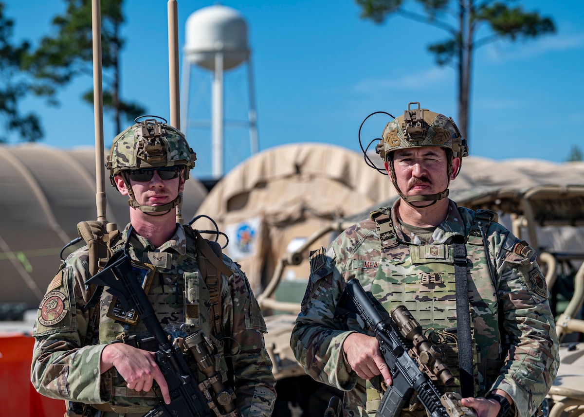 U.S. Air Force Staff Sgt. Zachary Ayriss, 23d Combat Air Base Squadron, and Chief Master Sgt. Patrick Meade, 23d CABS senior enlisted member, pose for a photograph outside the main operating base for exercise Mosaic Tiger 26-1 at the Combat Support Training Range at Tyndall Air Force Base, Florida, Nov. 20, 2025. Ayriss is manning the Joint Counter Radio-Controlled Improvised Explosive Device Electronic Warfare system for drone defense, providing a pivotal role in the night attack of Nov. 19 that tested the defense capability of CABS Airmen. (U.S. Air Force photo by Senior Airman Leonid Soubbotine)