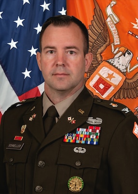 Photo of a soldier in uniform with the American flag on the left and a Signal Regimental flag on the right