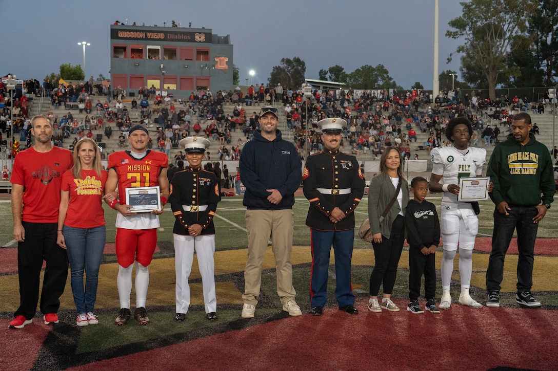 U.S. Marines with Recruiting Station Orange County pose for a photograph with Scholar Athletes and their families during a Great American Rivalry Series game in Mission Viejo, California, Oct. 10, 2025. The Great American Rivalry Series shines the spotlight on top high school football rivalries across the nation, where long-standing traditions are valued, expectations are sky high, and followers are passionate and loyal. (U.S. Marine Corps photo by Sgt. Fred Garcia)