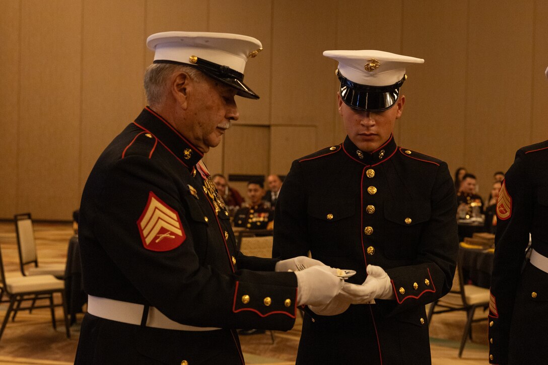 U.S. Marine Corps Sgt. Ruben Ramirez, oldest Marine present, passes a piece of cake to Pvt. Ivan Mayercasillas, youngest Marine present, during the cake cutting portion of Recruiting Station Riverside’s 250th Marine Corps Birthday Ball ceremony in Temecula, California, Nov. 10, 2025. The Marine Corps Birthday Ball celebrates the history, legacy, and traditions passed down through generations. (U.S. Marine Corps photo by Cpl. Osmar Gutierrez)