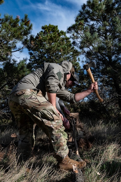Tech. Sgt. Brett Darby, 5th Operational Support Squadron survival, evade, resistance, escape specialist, shows airmen participating in the combat survival training how to properly build shelter at Garrison, North Dakota, Oct. 9, 2025. In order to better prepare for real-world survival situations, the refresher training helps aircrew hone their skills. (U.S. Air Force photo by Senior Airman Alyssa Bankston)