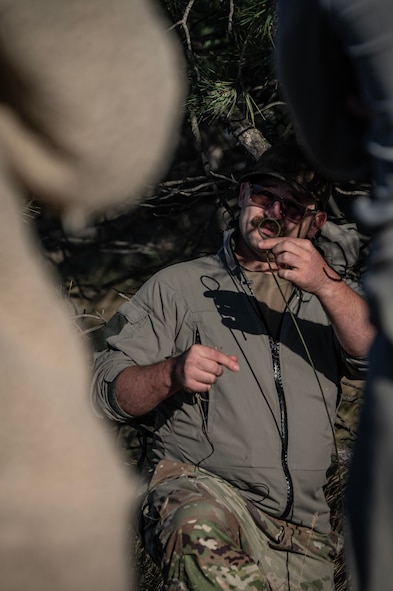 Tech. Sgt. Brett Darby, 5th Operational Support Squadron survival, evade, resistance, escape specialist, shows airmen participating in the combat survival training how to properly build shelter at Garrison, North Dakota, Oct. 9, 2025. SERE specialists are responsible for equipping Air Force aircrew with the necessary abilities to live in the wild and in hostile territory in the event that pilots are forced to land. (U.S. Air Force photo by Senior Airman Alyssa Bankston)